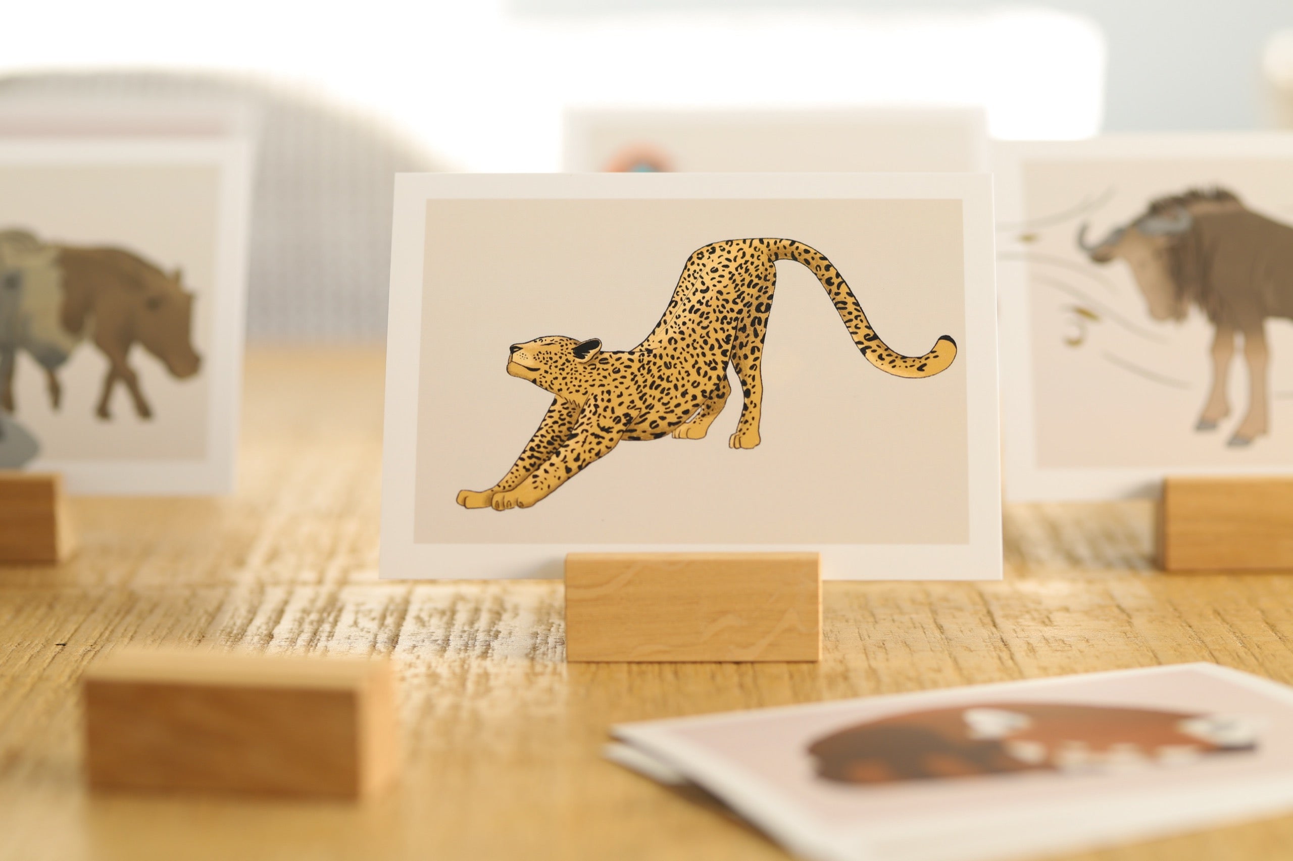 Das Bild zeigt verschiedene Gefühlskarten. Im Vordergrund ist eine Karte scharf gestellt. Auf dieser ist ein sich beugender Leopard zu erkennen, der ein Gefühl ausdrückt. Die Karte ist in einem Kartenhalter aus Holz eingesteckt.