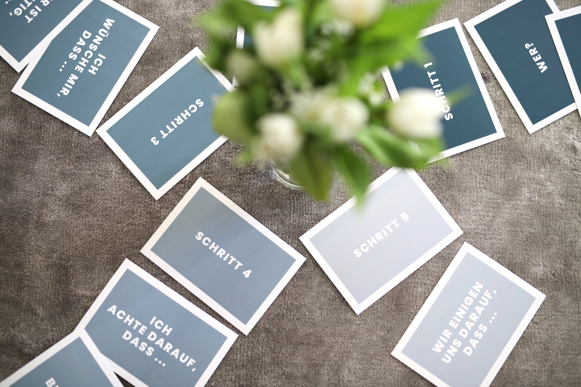 Das Foto zeigt einen Blumenstrauß von oben um den herum Karten gelegt sind. Alle Karten haben eine individuelle Aufschrift zur Konfliktlösung. 